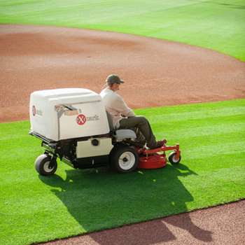 Groundskeeper mowing baseball field with a Exmark Navigator Professional Grade zero-turn mower