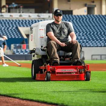 Groundskeeper mowing grass on baseball field with a Exmark Navigator zero-turn mower